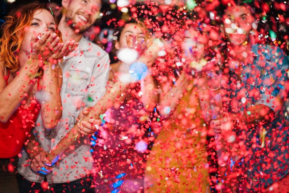 Happy friends celebrating with confetti new year's eve inside disco club - Party concept - Soft focus on left girl face